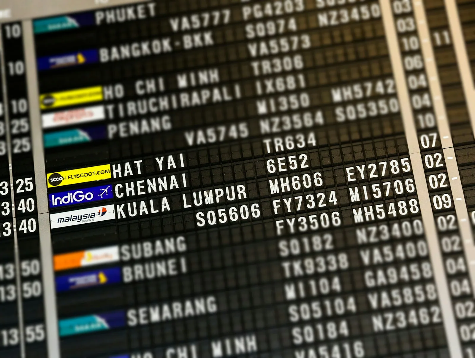 An airport departures board listing Southeast Asian destinations including Bangkok, Ho Chi Minh, Penang and Kuala Lumpur | BudgetBro