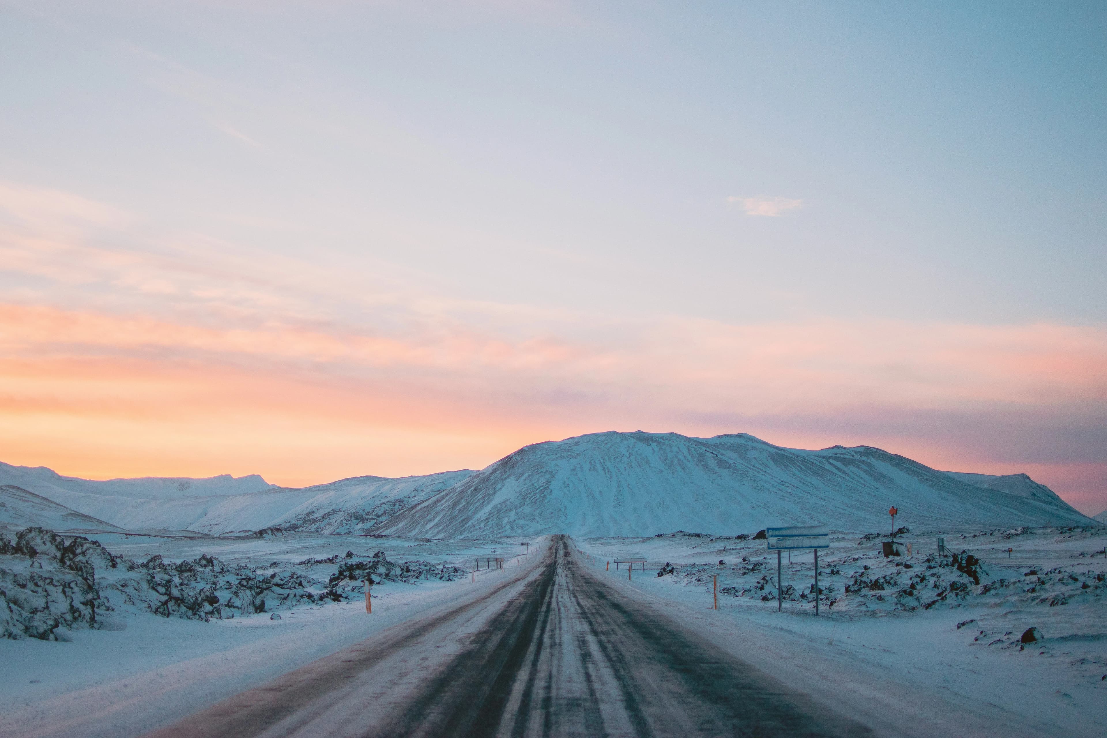 An Icelandic road stretching toward snow covered mountains near the Snaefellsnes Peninsula at sunset | BudgetBro