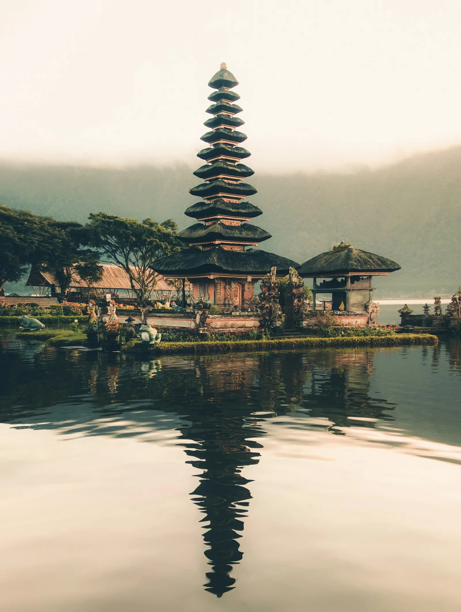 The Ulun Danu Beratan temple reflected in the still water of a lake in Bali, Indonesia, in soft morning light | BudgetBro