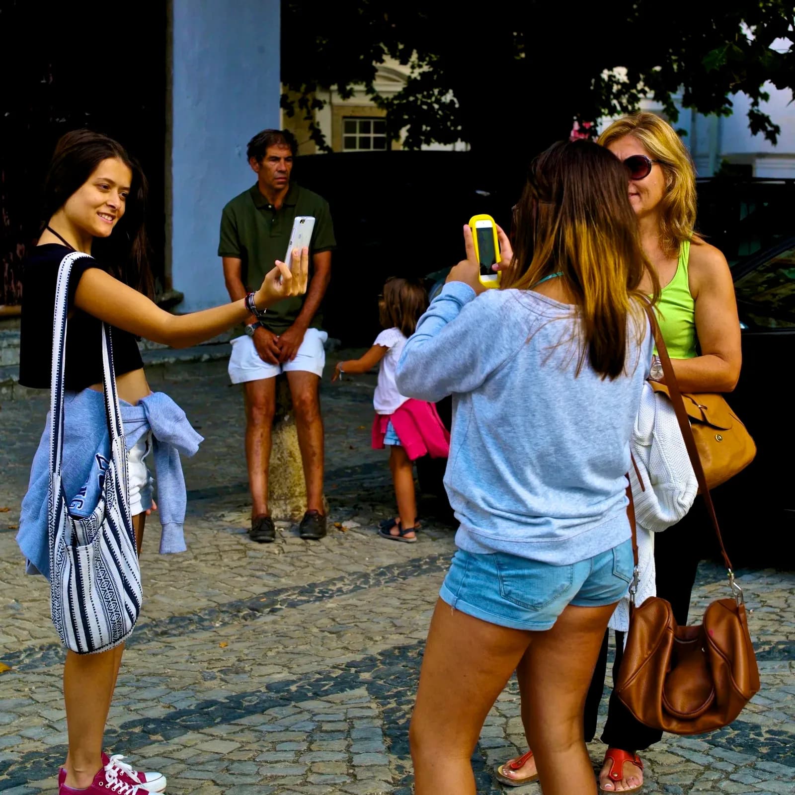 A group of tourists taking photos with their smartphones on a cobbled street | BudgetBro