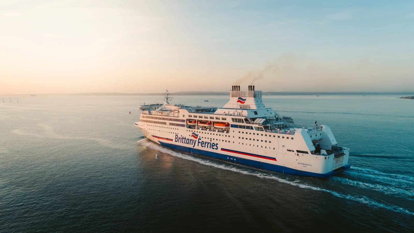 A large passenger ferry sailing across calm sea waters at sunrise, photographed from the air near Portsmouth | BudgetBro