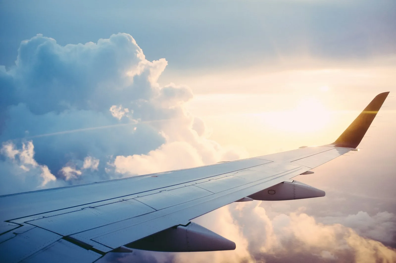 An aircraft wing above the clouds at sunset, on approach to a destination | BudgetBro