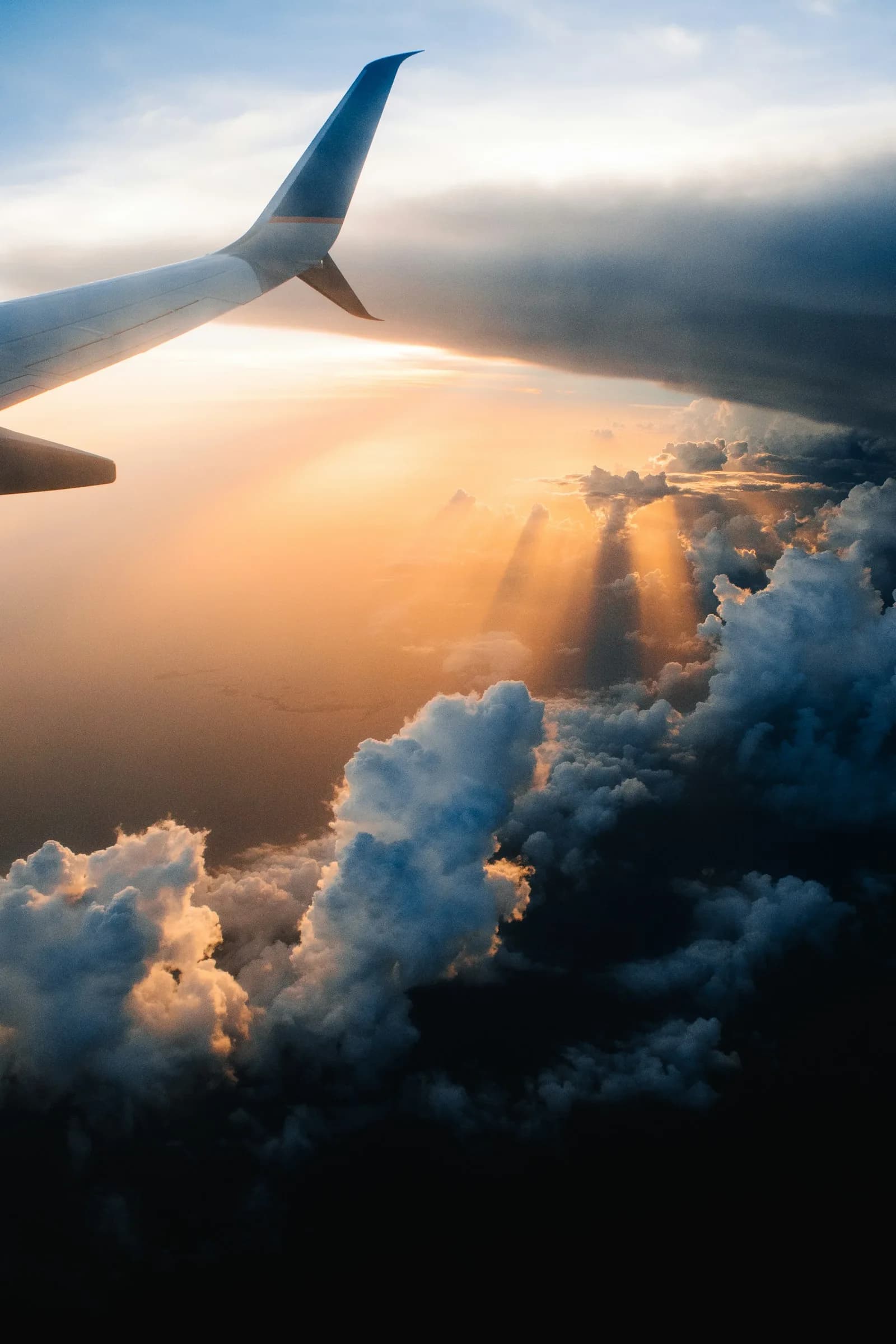 An aircraft wing above the clouds at sunset on the approach to a destination | BudgetBro
