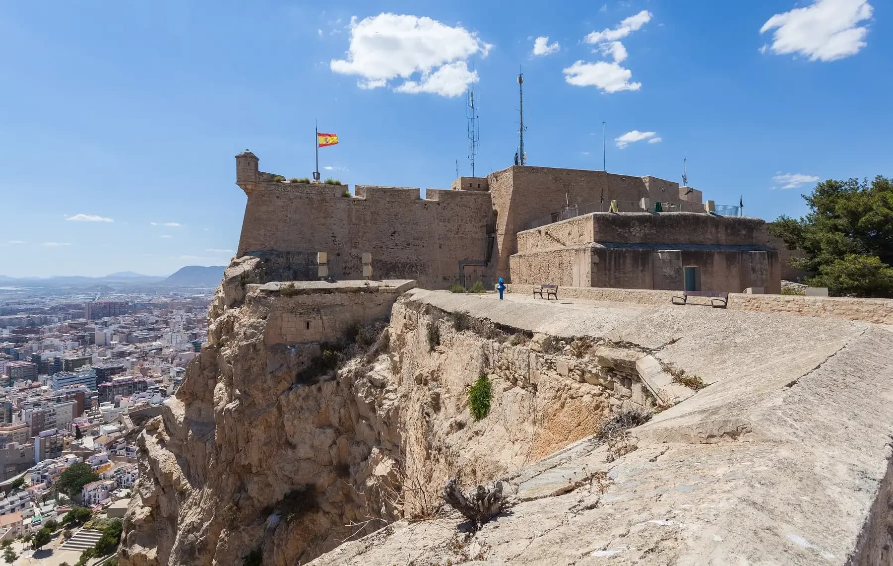 Castillo de Santa Bárbara walls and Spanish flag high above the rooftops of Alicante | BudgetBro