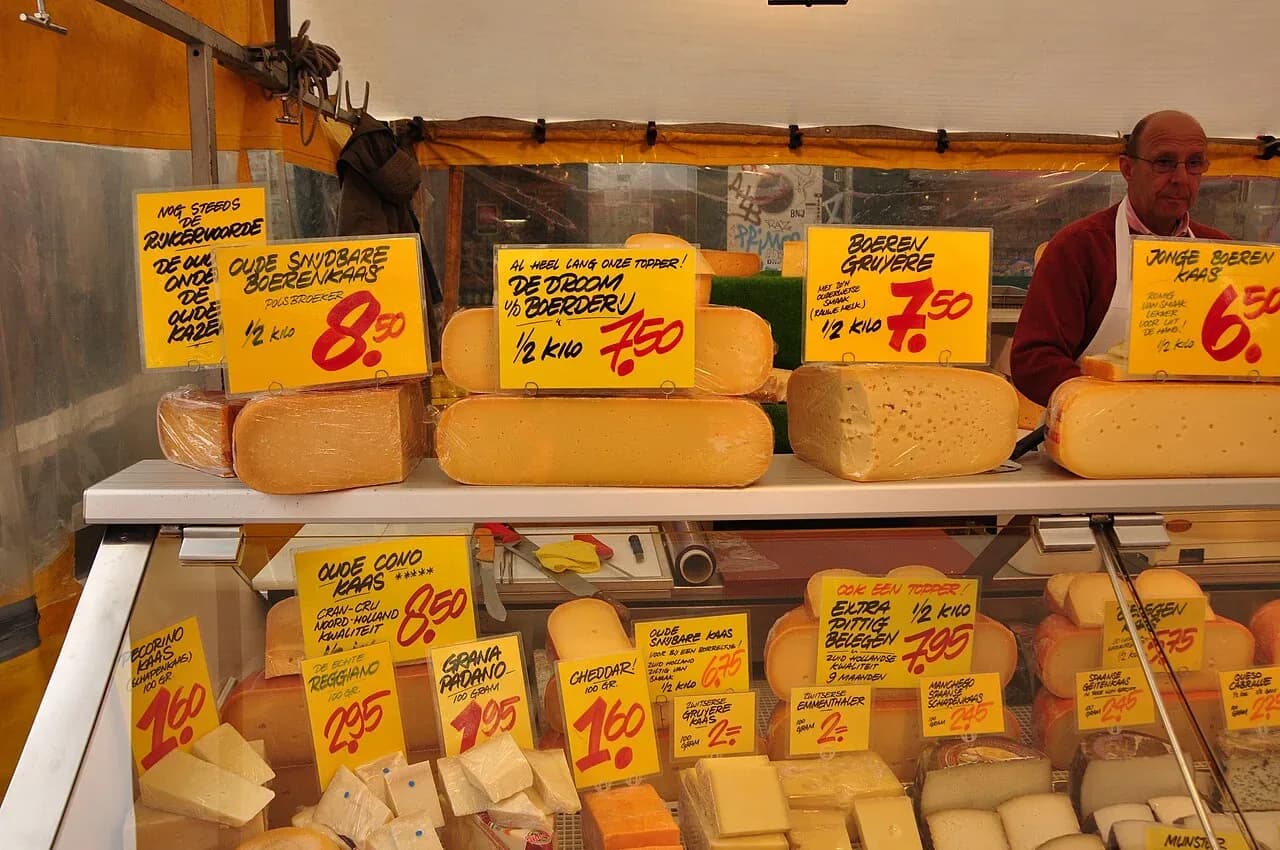 Cheese stall with price signs at the Albert Cuypmarkt in Amsterdam | BudgetBro
