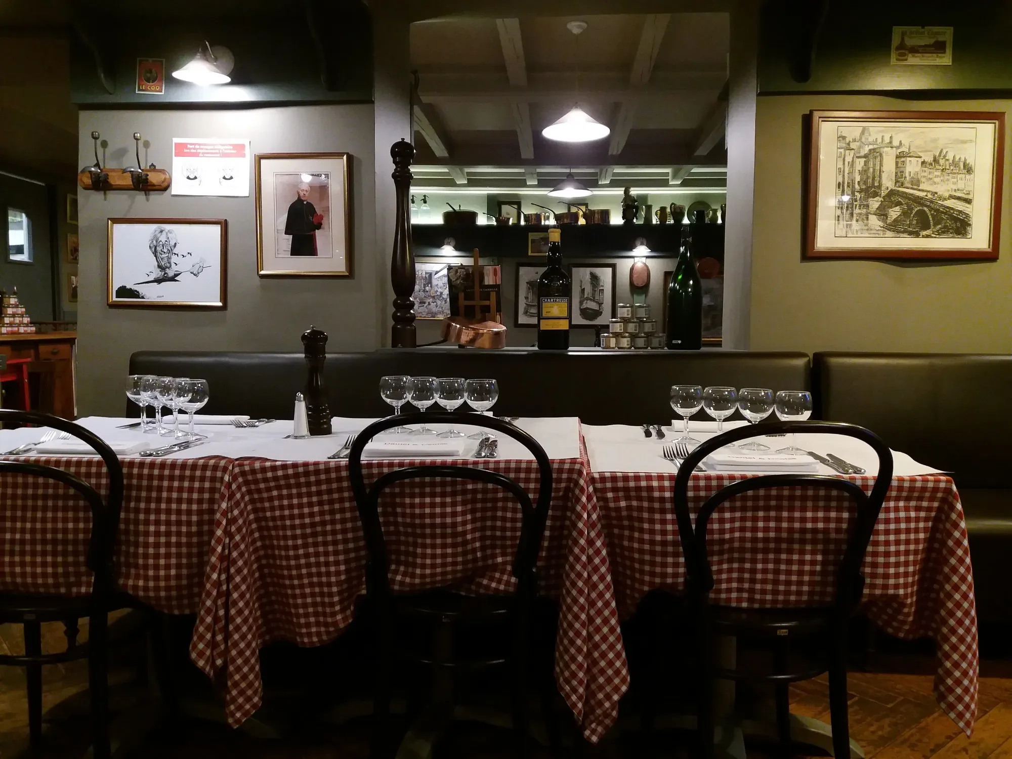 Inside a Lyon bouchon in Vieux Lyon, tables laid with red and white checked cloths and wine glasses | BudgetBro