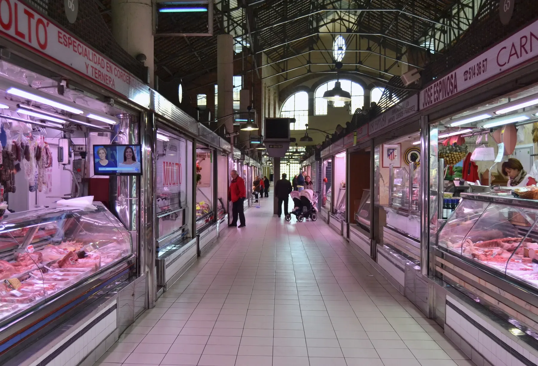 Inside Alicante's Mercado Central, rows of lit butcher and deli counters under the market roof | BudgetBro