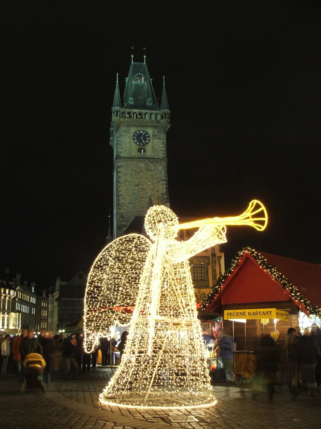 Lit-up angel decoration in front of the Old Town Hall tower in Prague at night | BudgetBro