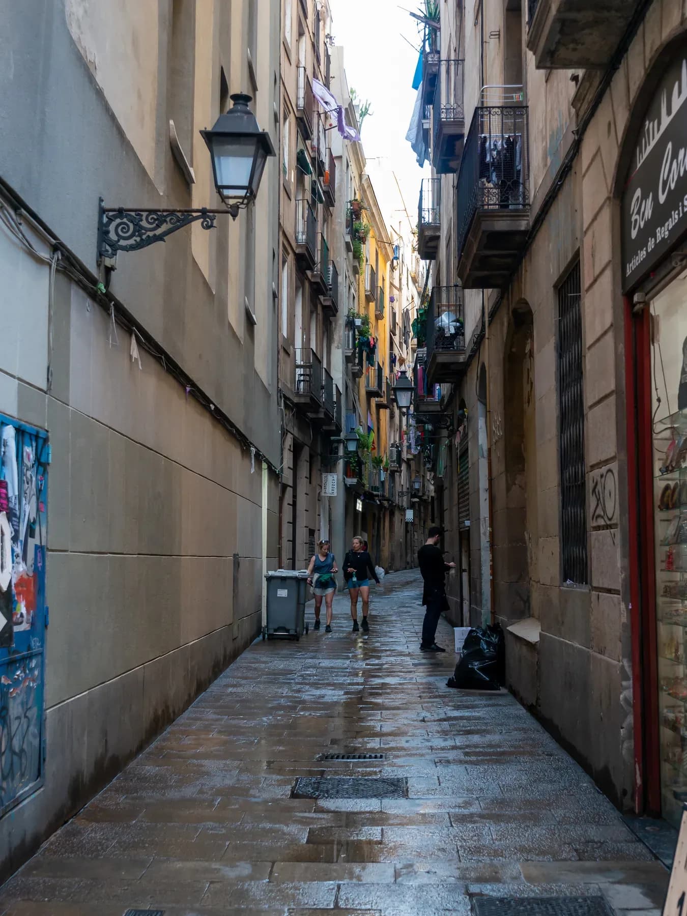 Narrow stone street in Barcelona's Gothic Quarter with iron balconies and street lamps | BudgetBro