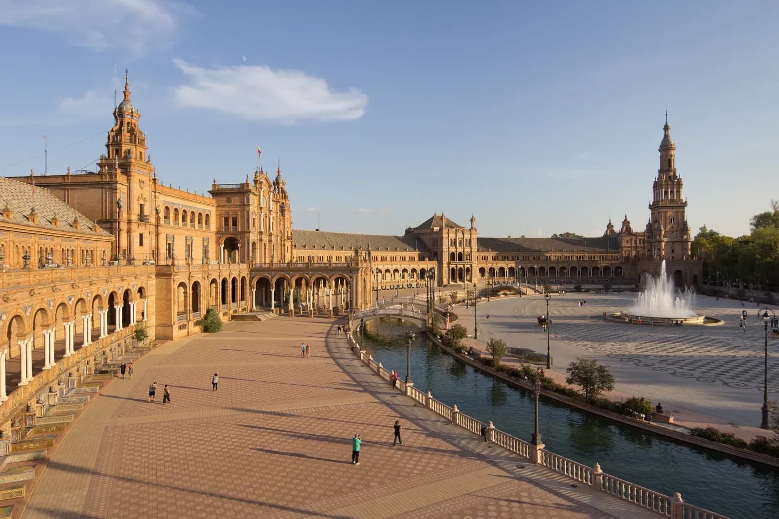Plaza de España in Seville with its curved brick buildings, canal and fountain in evening sun | BudgetBro