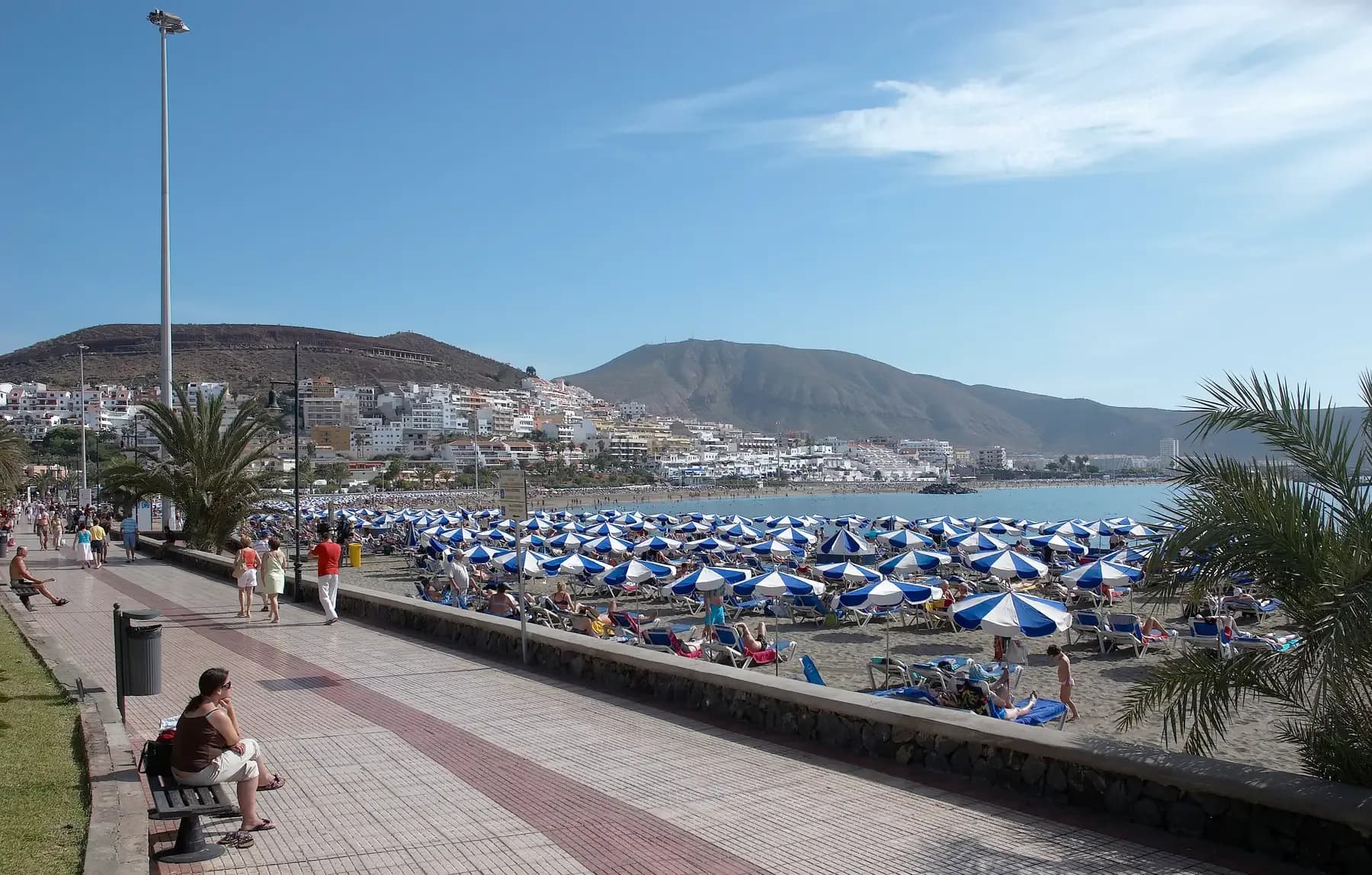 Seafront promenade and beach umbrellas at Los Cristianos in Tenerife on a sunny day | BudgetBro
