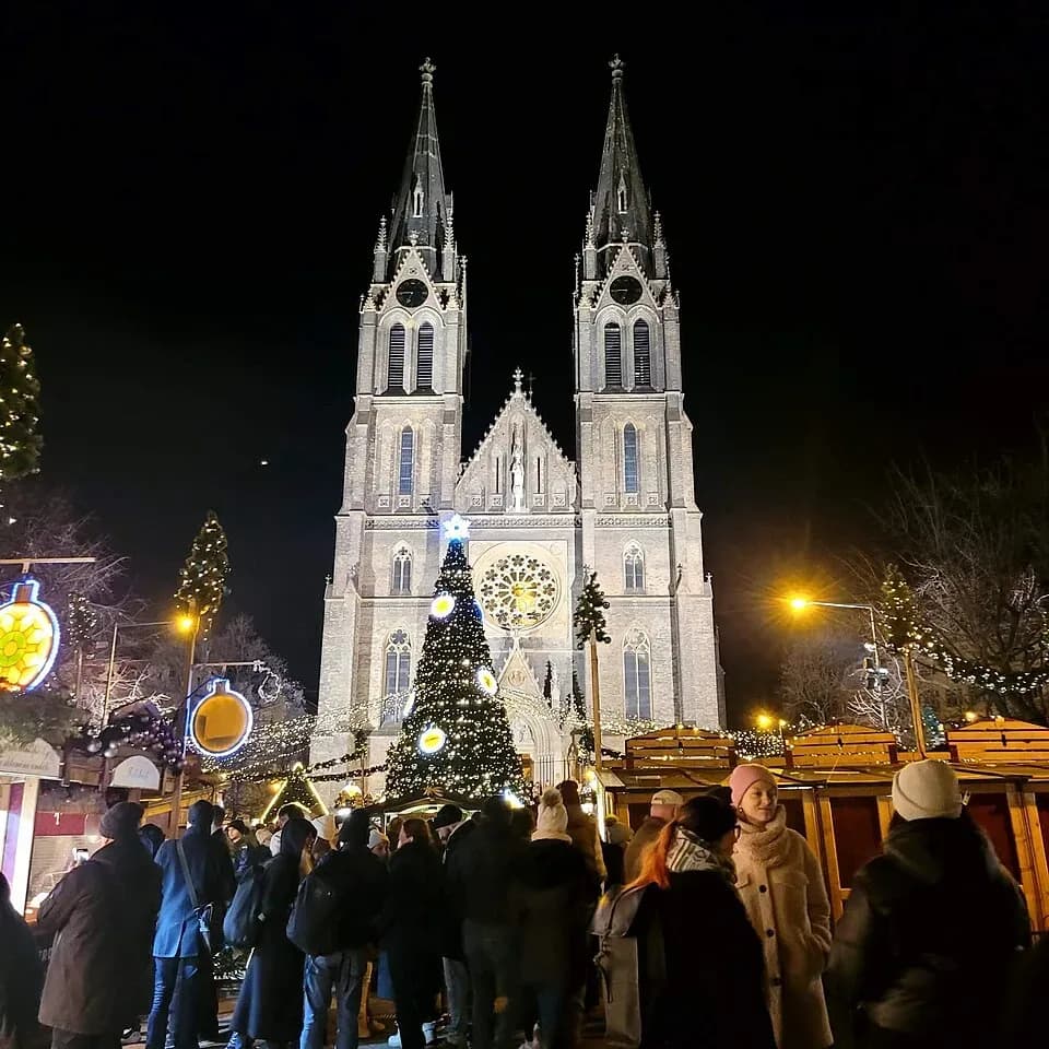 The Christmas market on Náměstí Míru in Prague at night, with the Church of St Ludmila behind | BudgetBro