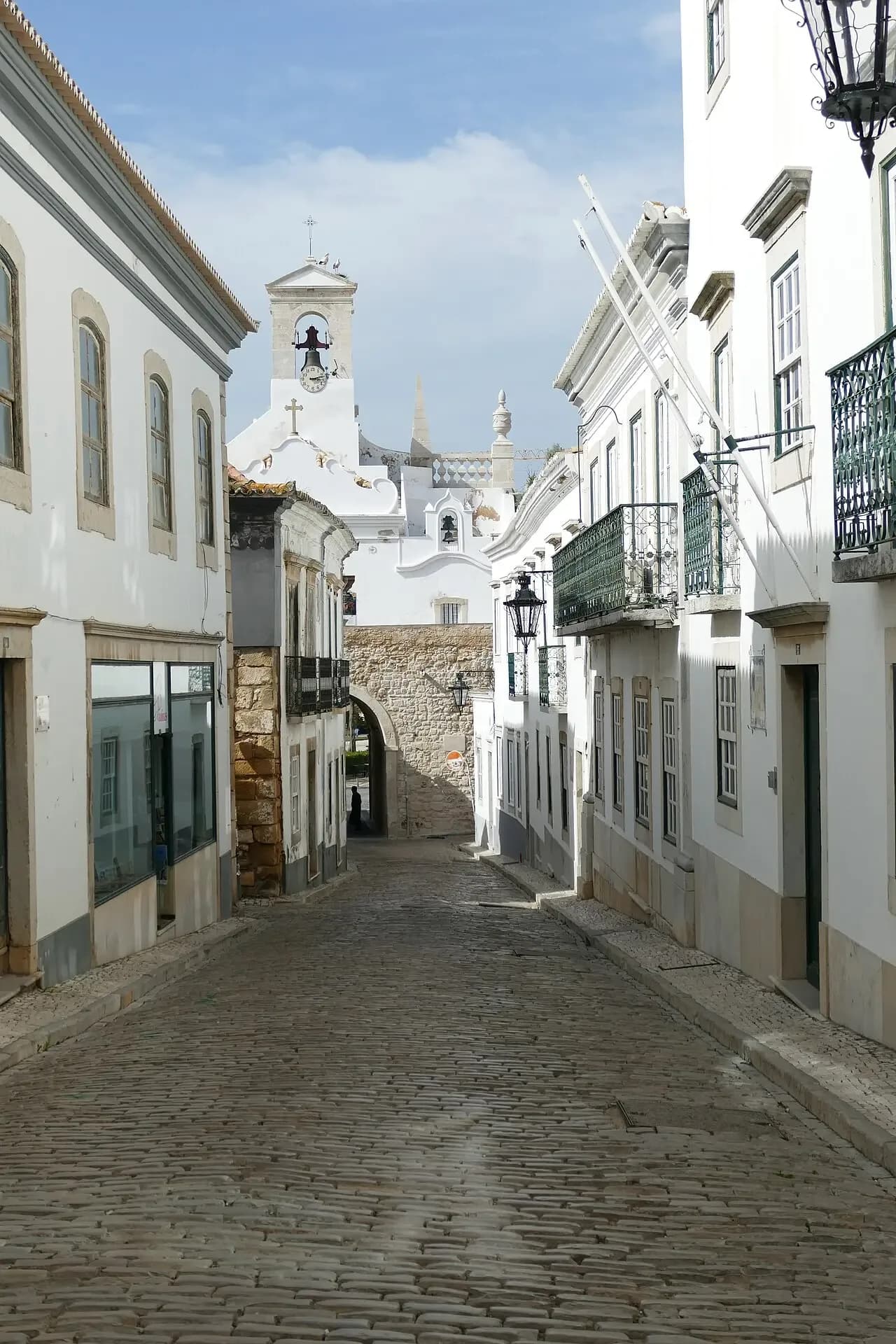 Whitewashed street in Faro's old town leading to the Arco da Vila gate | BudgetBro